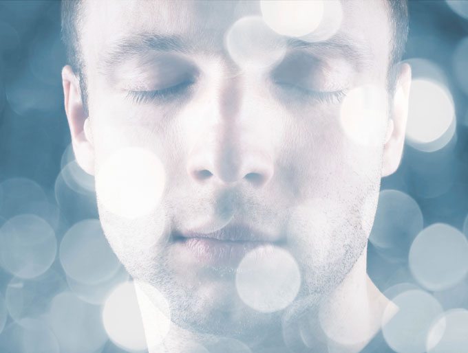 creative visualization, face of man with eyes closed and circles of light.