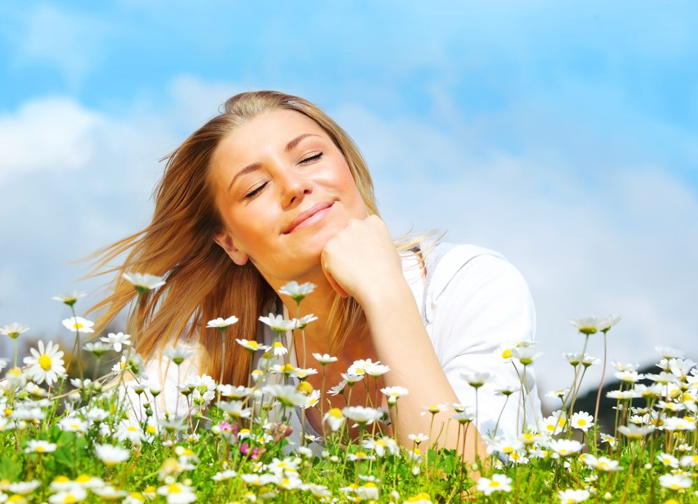 visualization techniques woman smiling laying in flowers under blue sky