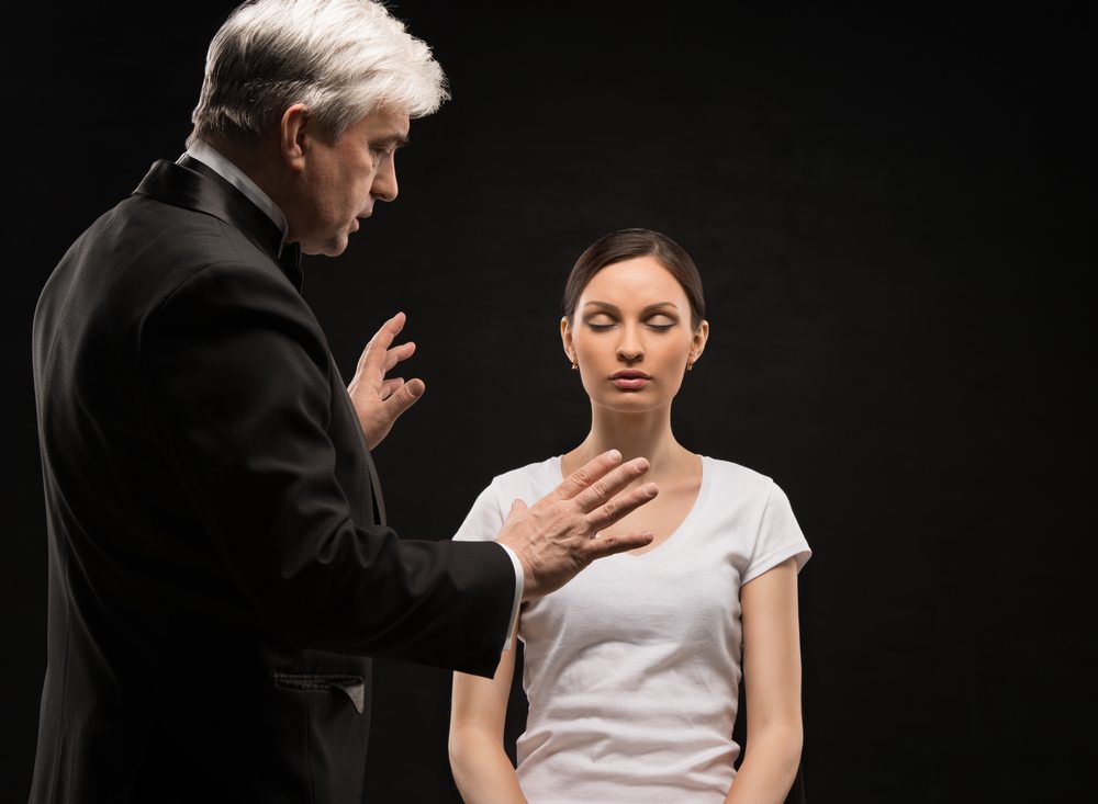 What is hypnosis? Cliche image of a hypnotist, wearing a tuxedo, hypnotizing a women