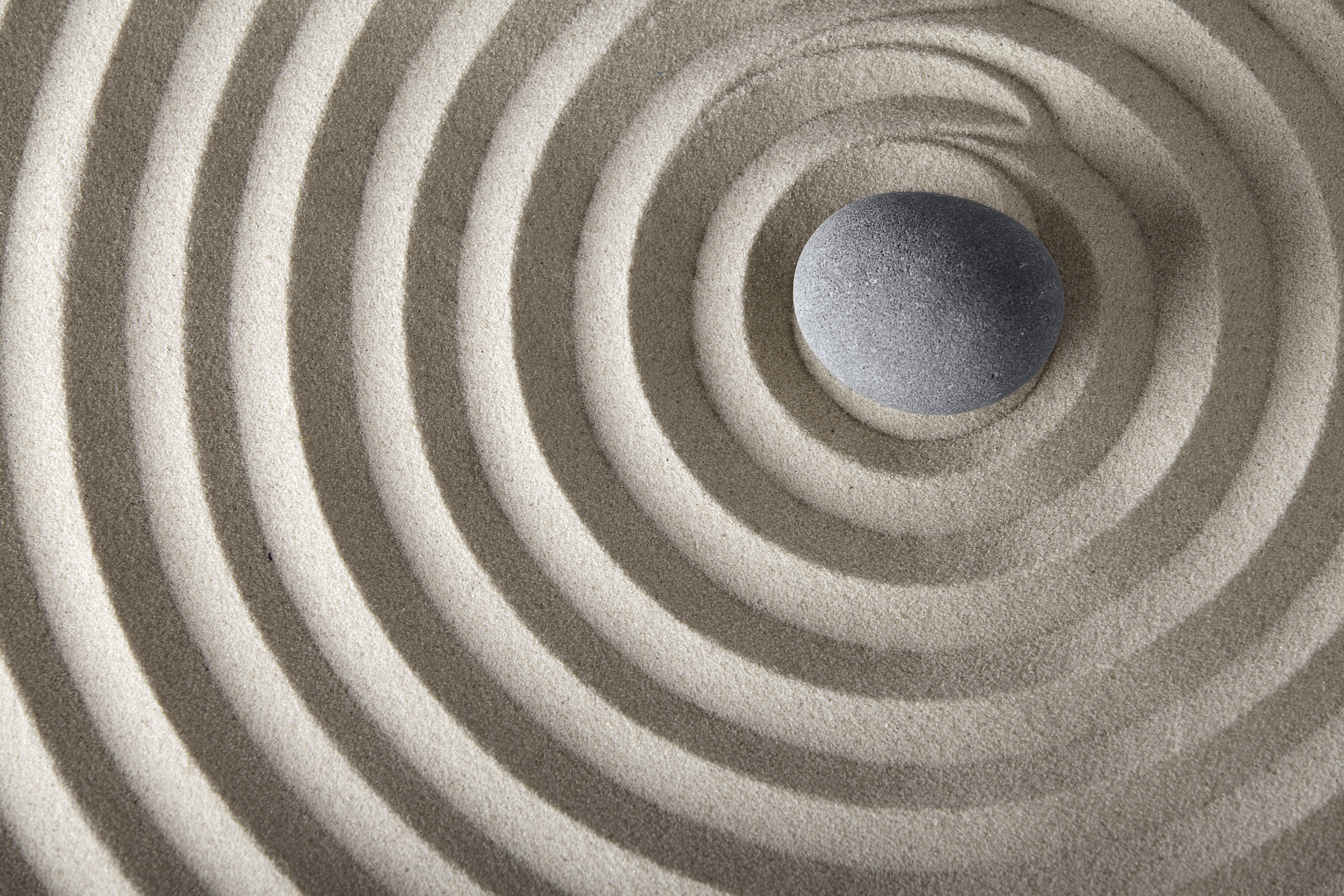 The power of the mind -a zen sand swirl with a stone set off center right