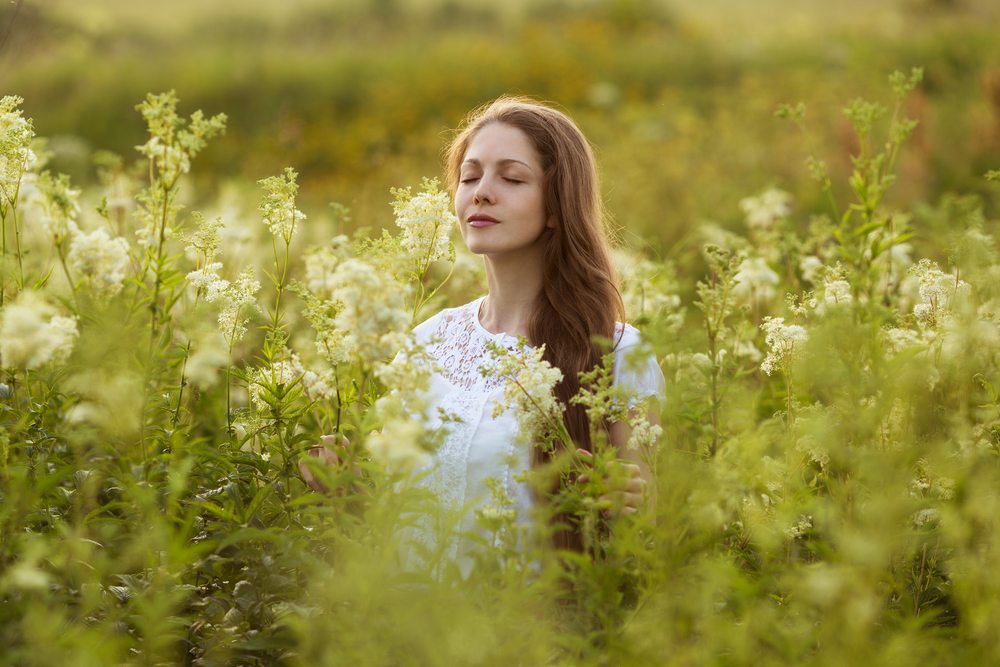 Psychic Abilities, a women sitting with her eyes closed in a field of wild white flowers