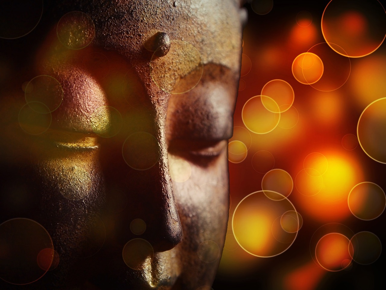 Psychic Abilities, Close up image of a bronze Buddha face with orange camera light flares