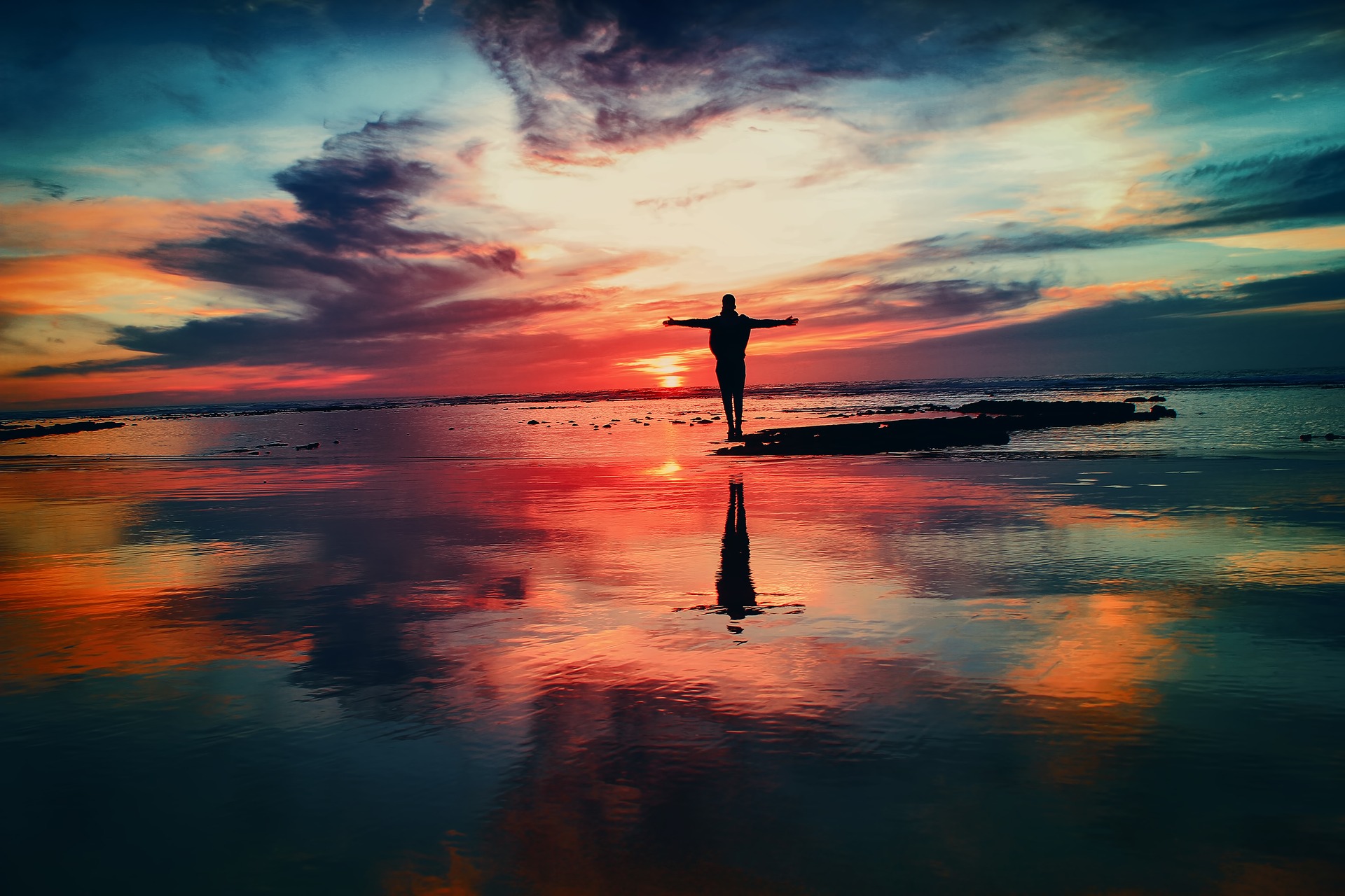 Self Hypnosis Audio -A person standing on the beach just after sunset with purple, blue, orange and red clouds