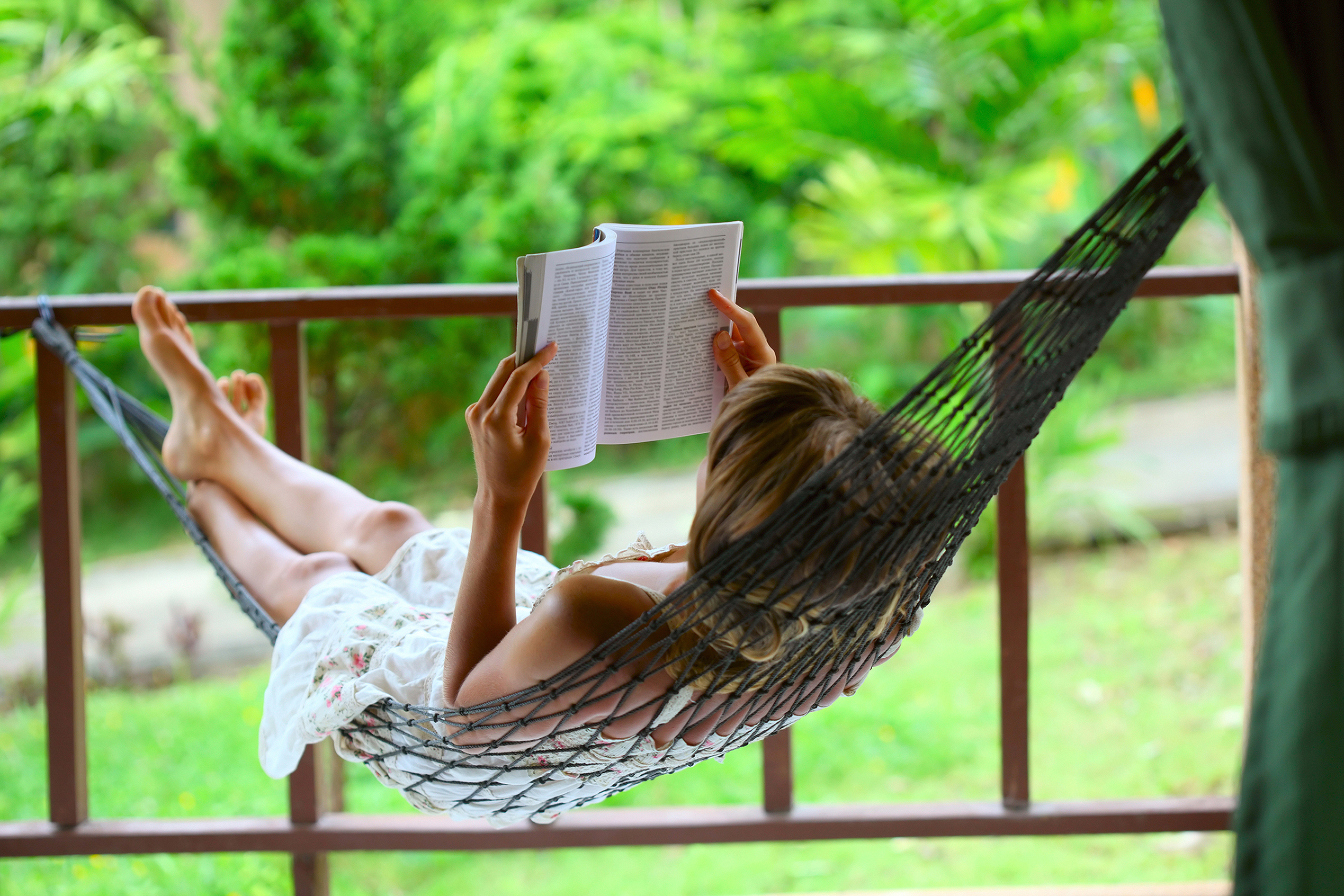 Mind power techniques Young woman reading a book lying in hammock