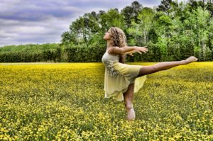 manifesting abundance woman dancing in field